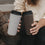 Zwei To-go-Thermobecher in Braun und Beige mit Herzmotiv und schwarzem Deckel