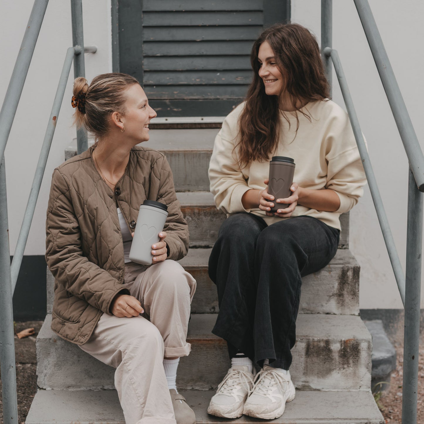 Zwei Frauen mit braunem und beigem To-go-Thermobecher mit Herzmotiv