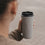 Grauer To-go-Thermobecher mit Herzmotiv und schwarzem Trinkdeckel in der Hand