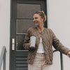 Frau mit grauem To-go-Thermobecher mit Herzmotiv und schwarzem Deckel