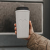 Grauer To-go-Thermobecher mit Herzmotiv und schwarzem Deckel in Nahaufnahme