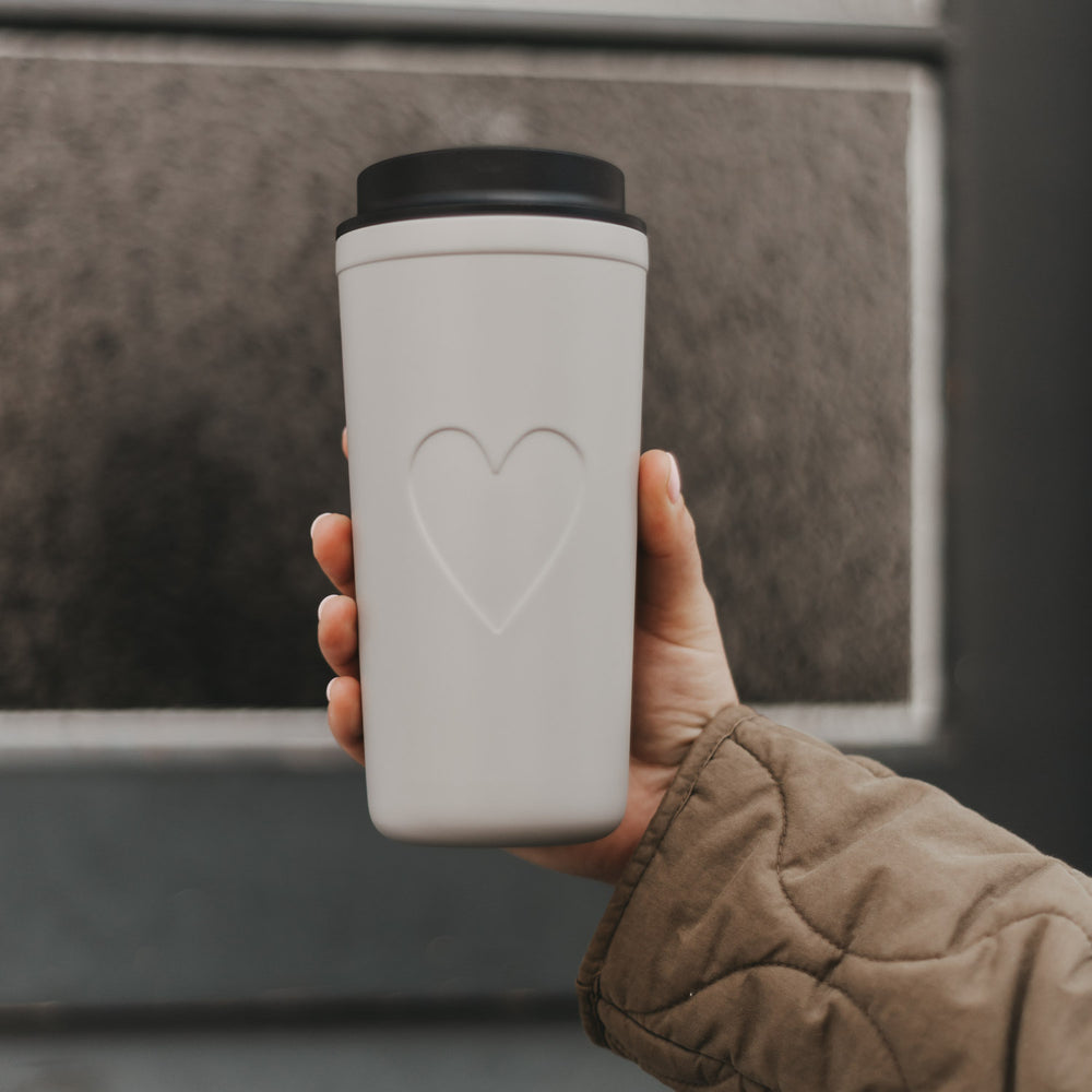 Grauer To-go-Thermobecher mit Herzmotiv und schwarzem Deckel in Nahaufnahme