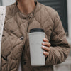 Grauer To-go-Thermobecher mit Herzmotiv in der Hand einer Frau
