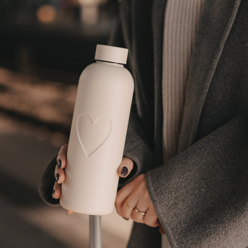 Trinkflasche Herz in Creme mit 500 ml Fassungsvermögen und geprägtem Herzmotiv in der Hand einer Frau