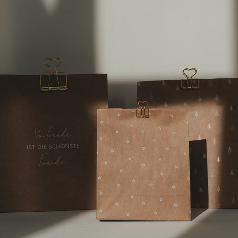 Goldene Herz-Clips befestigen dekorative Geschenktüten und Papierverpackungen mit weihnachtlichen Motiven.