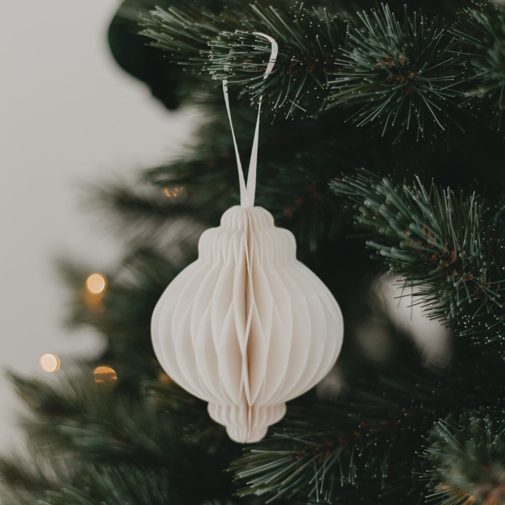 Naturfarbener Papieranhänger hängt an Tannenzweig, dekoriert am Weihnachtsbaum mit Lichtern