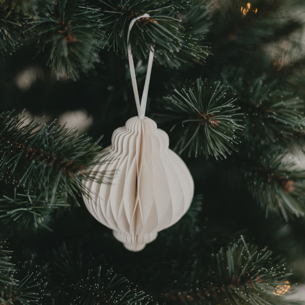 Detailansicht eines Papieranhängers in Naturfarbe am grünen Weihnachtsbaum, elegant und schlicht