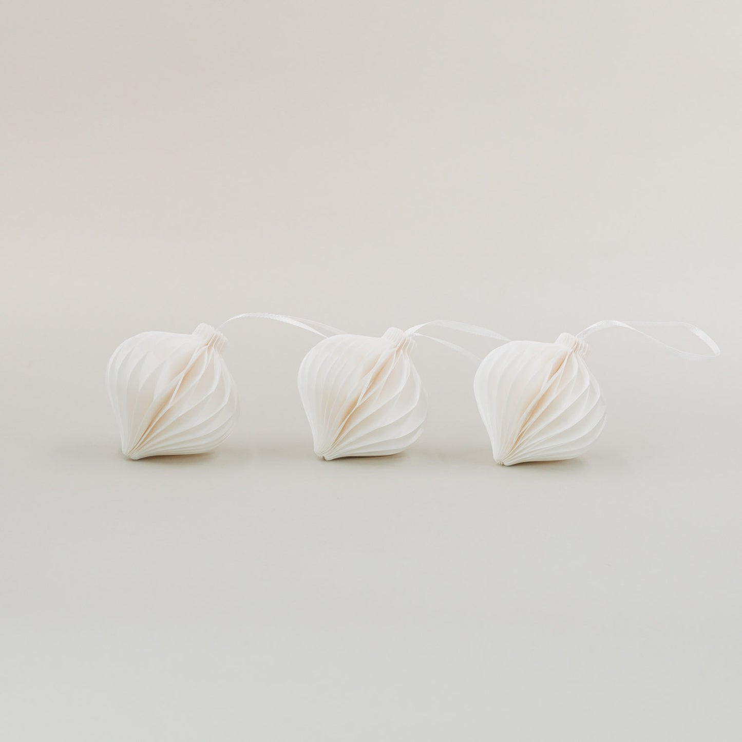 Drei weiße Papieranhänger im 3er-Set mit Wabenstruktur für stilvolle Weihnachtsdekoration auf hellem Hintergrund