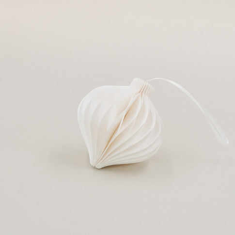 Ein weißer Papieranhänger in Tropfenform mit feiner Wabenoptik, liegend mit Band auf hellem Hintergrund