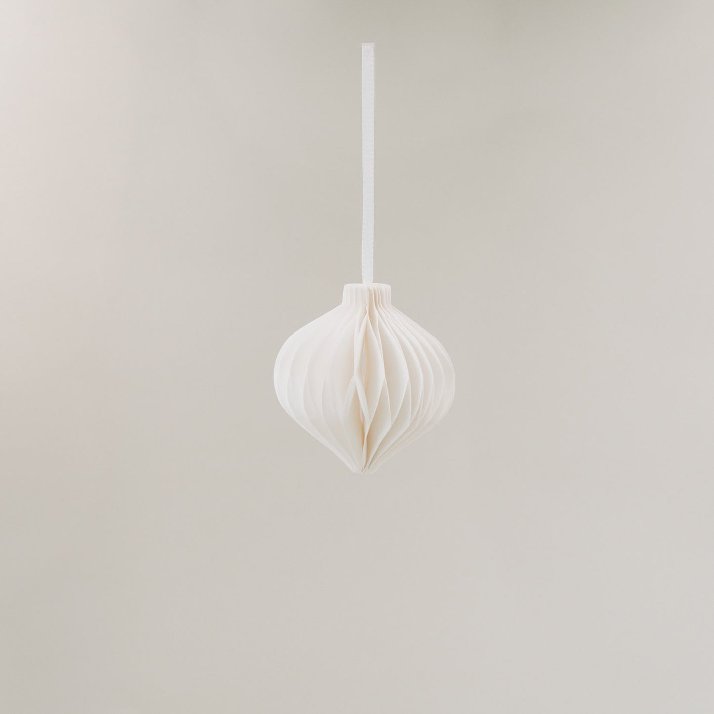 Weißer Papieranhänger hängend an weißem Band vor neutralem Hintergrund – elegant und minimalistisch