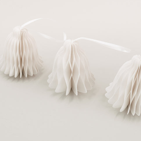 Nahaufnahme von drei Papierglocken in natürlichem Weiß mit filigraner Wabenstruktur auf hellem Untergrund.
