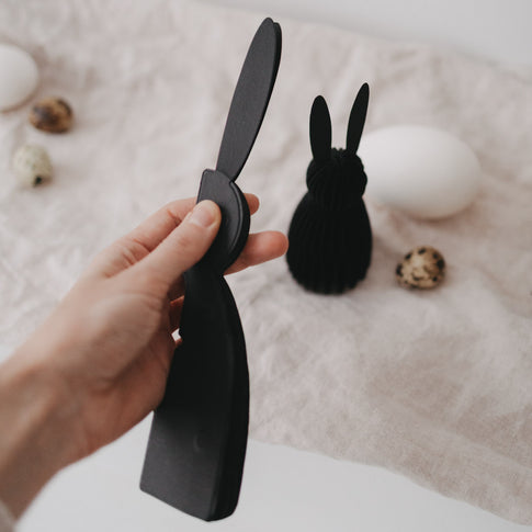 Hand hält schwarzen Papierhasen aus dem 2er-Set, detailreiche Nahaufnahme.