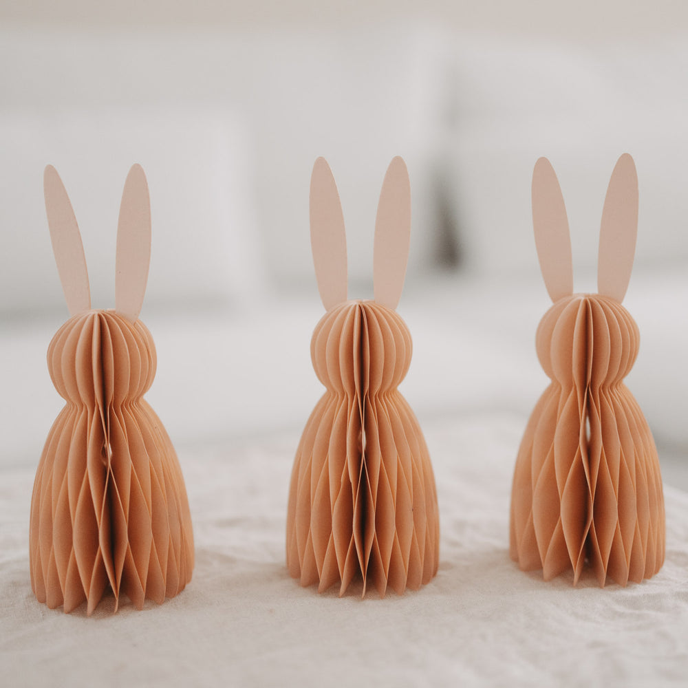 Peachfarbene Papierhasen im 3er-Set in Reihe stehend als minimalistische Osterdeko.