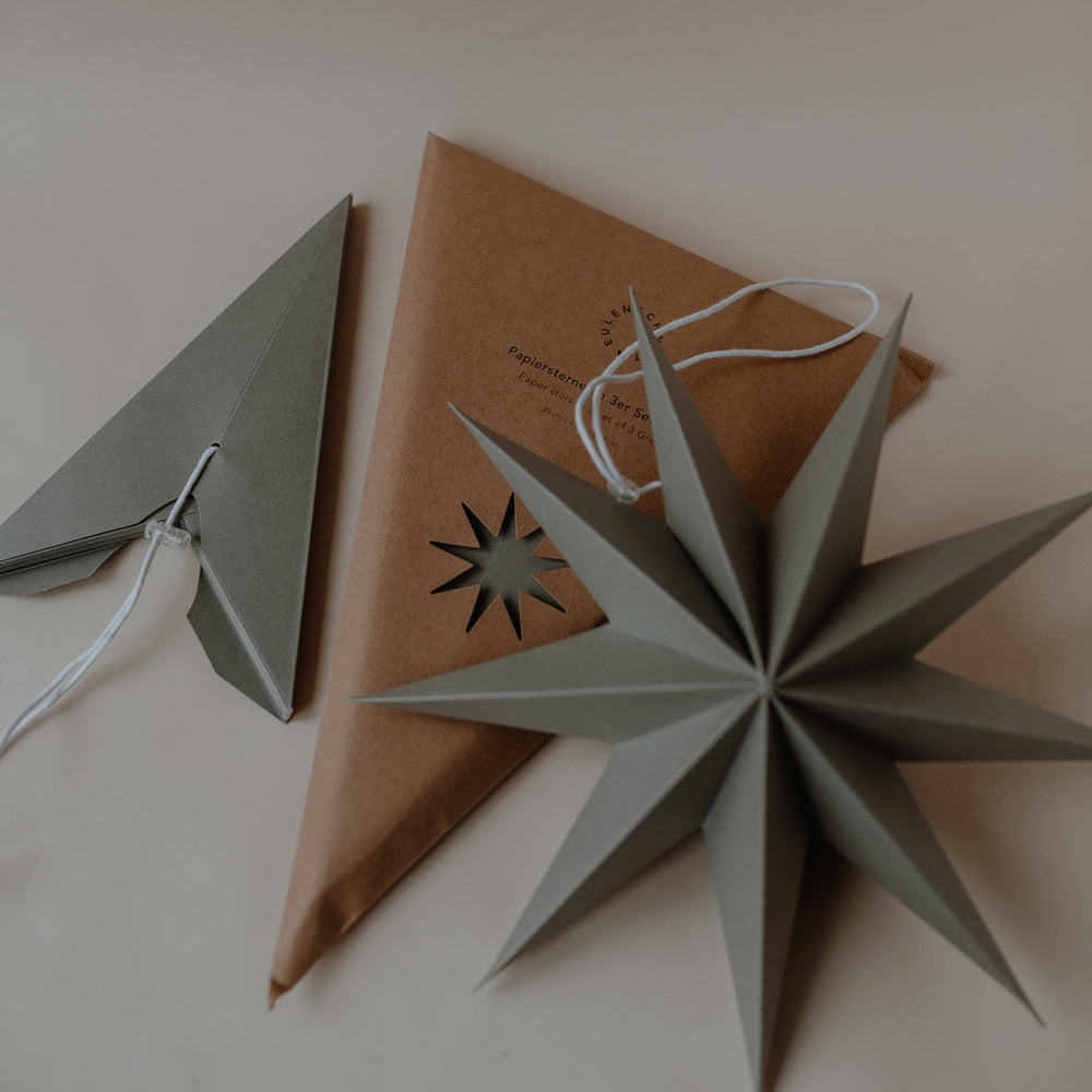 Graue Papiersterne in drei Größen mit Verpackung und Aufhängung als stilvolle Weihnachtsdekoration