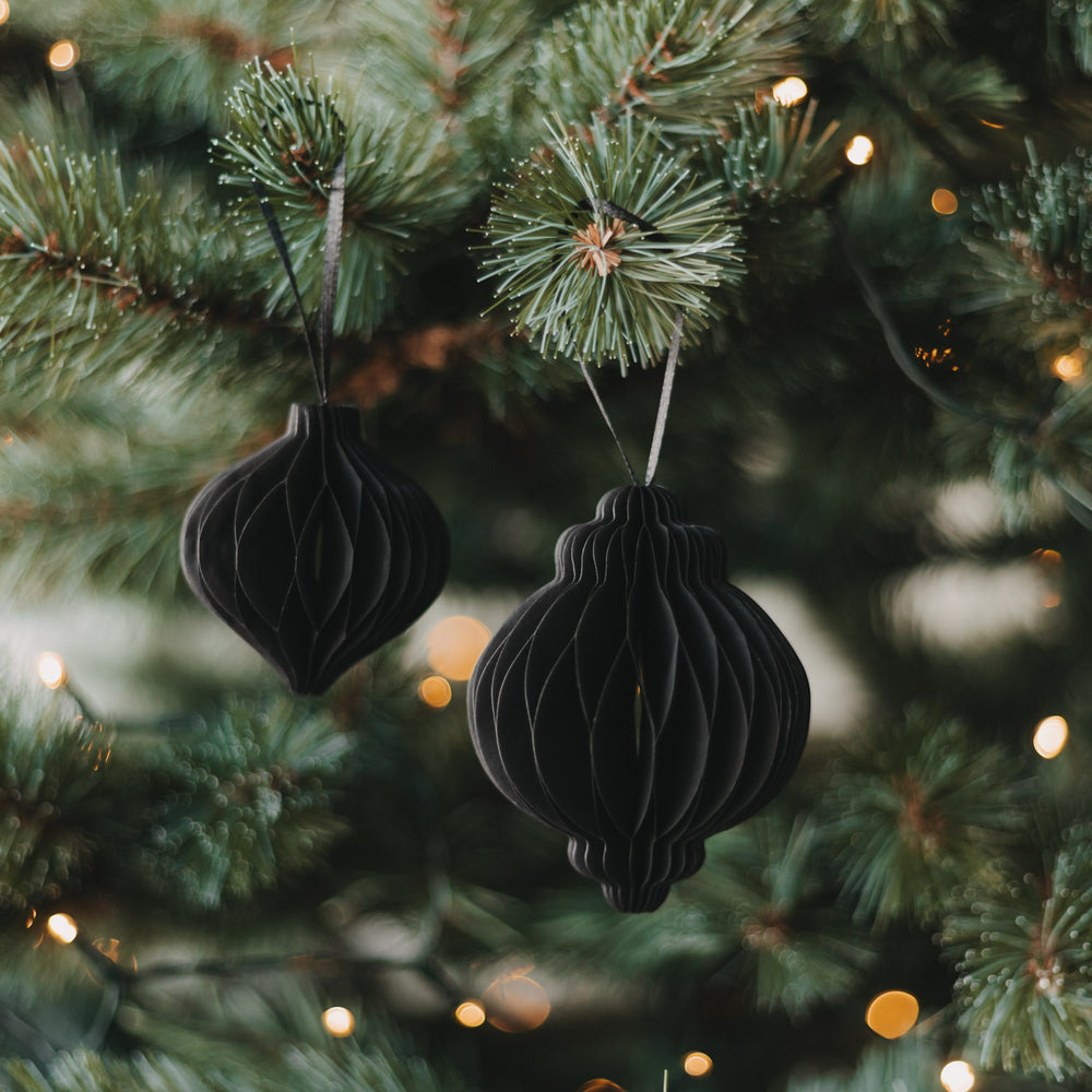 Zwei schwarze Papieranhänger in Kugelform als moderner Christbaumschmuck am Weihnachtsbaum