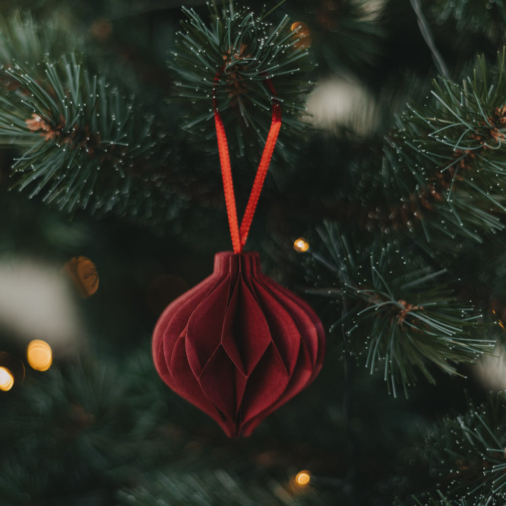 Roter Weihnachtsanhänger in Kugelform aus Papier am Tannenbaum