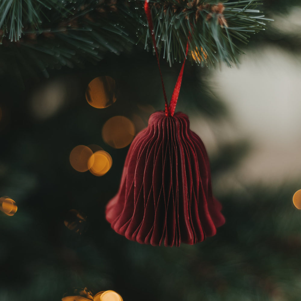 Rote Papierglocke als Weihnachtsanhänger am festlich geschmückten Christbaum