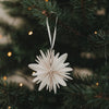 Naturfarbene Papierschneeflocke aus Papier als Weihnachtsbaumschmuck am Tannenzweig
