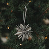 Graue Papierschneeflocke als Christbaumschmuck am festlich geschmückten Weihnachtsbaum