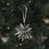 Graue Papierschneeflocke als Christbaumschmuck am festlich geschmückten Weihnachtsbaum