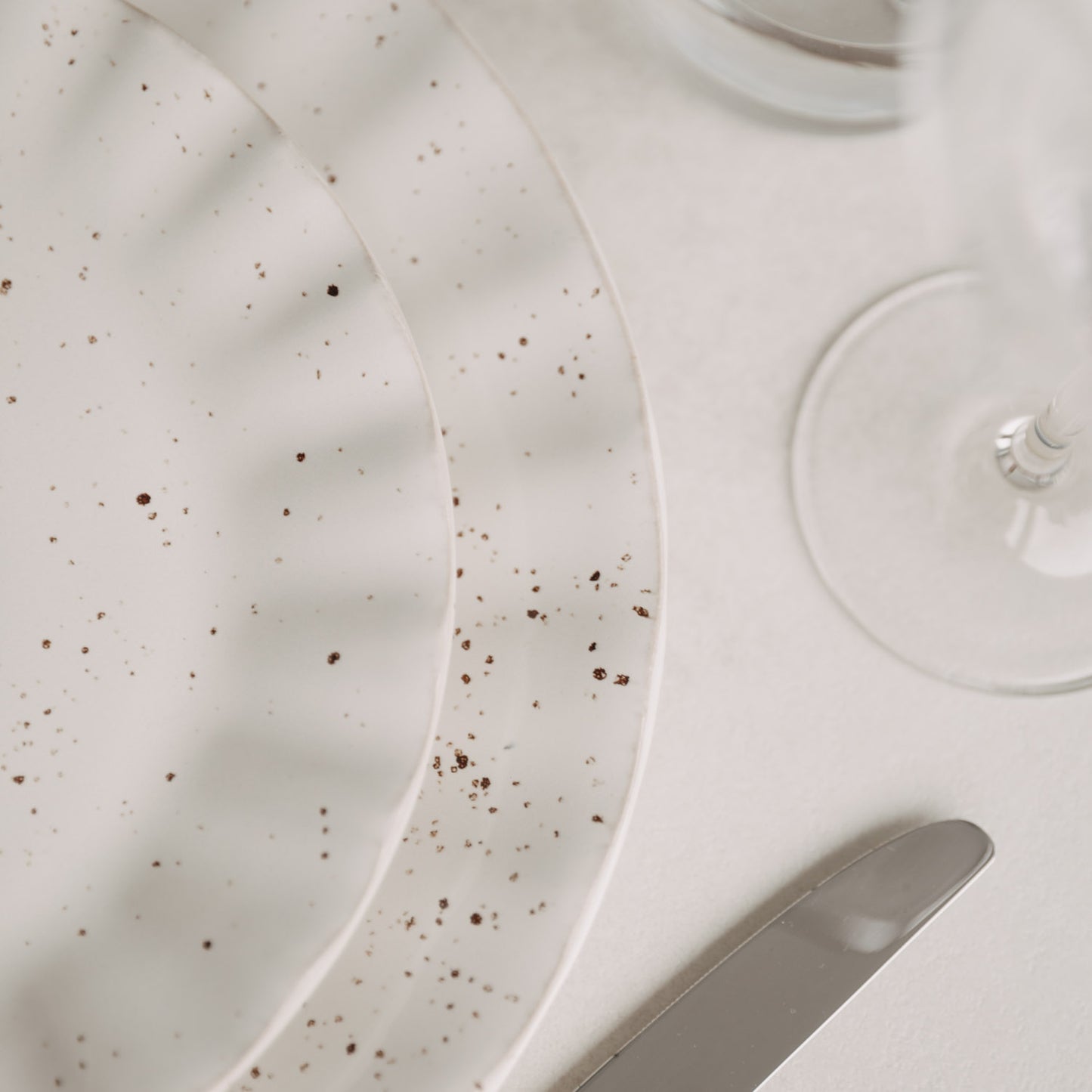 Detailaufnahme vom gedeckten Tisch mit Fokus auf den Colina-Teller und Glasrand