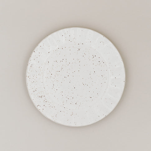 Speiseteller Colina von oben mit gesprenkelter Glasur und welligem Rand auf hellem Untergrund