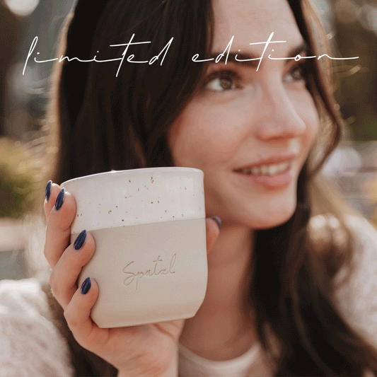 Frau hebt lächelnd Becher mit „Spatzl“-Prägung, Schriftzug „limited edition“ erscheint animiert im Bild.