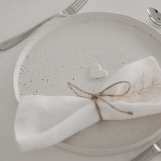 Calma Speiseteller mit Herzprägung auf festlich gedecktem Tisch mit Stoffserviette und Besteck