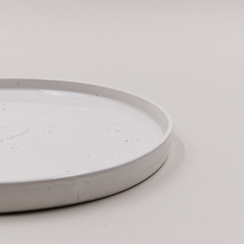 Nahaufnahme der erhöhten Tellerkante des Calma Frühstückstellers mit feinen braunen Sprenkeln.