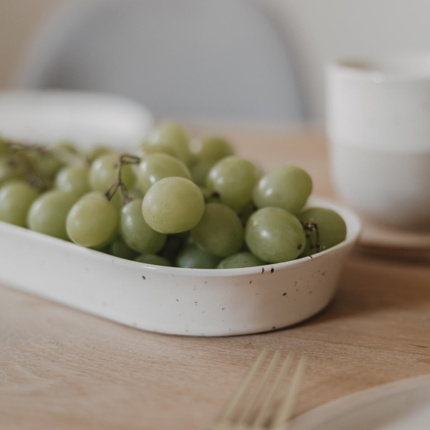 Seitliche Nahaufnahme der Servierschale Calma klein mit frischen Weintrauben auf dem Esstisch
