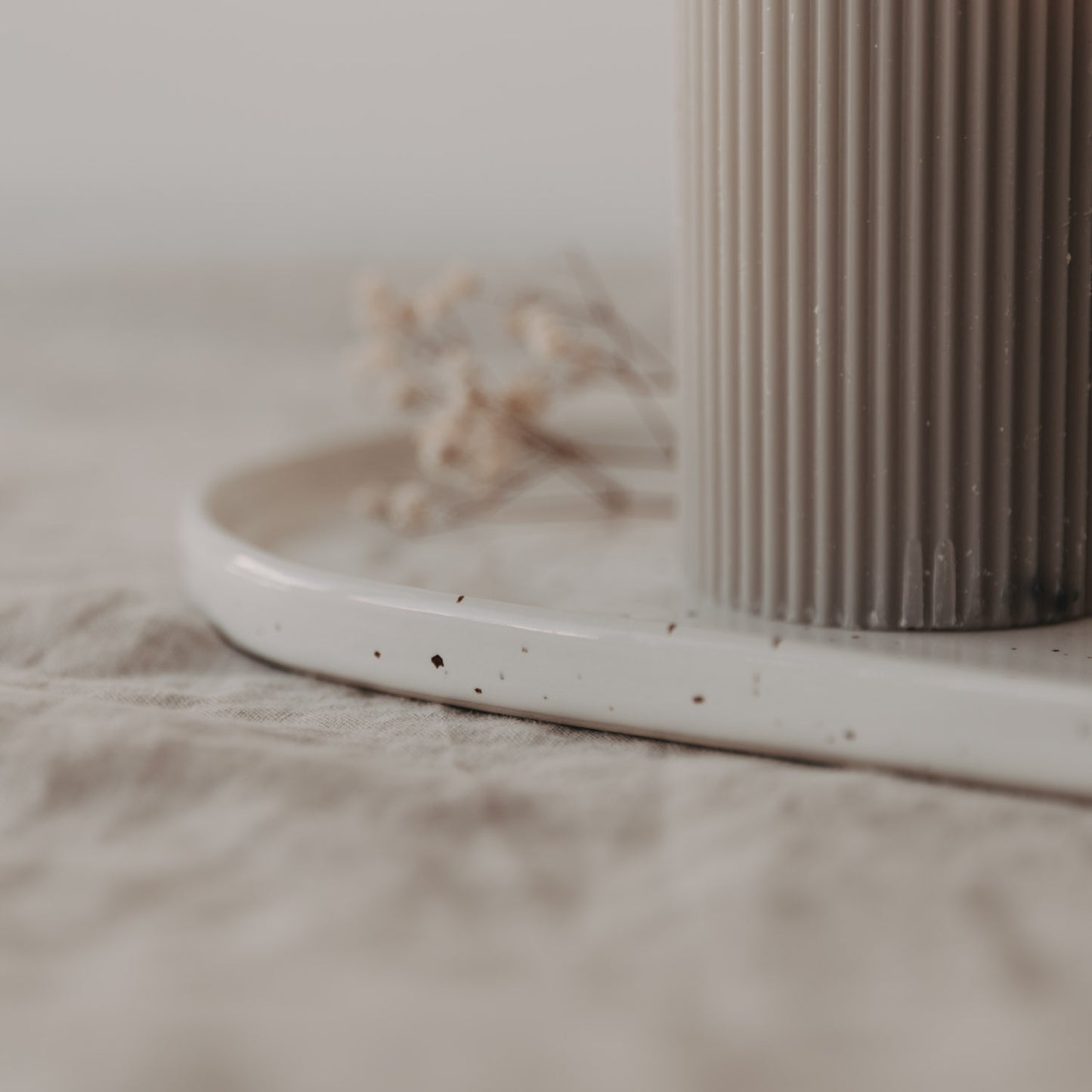 Detailaufnahme: Servierplatte Calma klein mit Kerze und getrockneter Blume – dezente Tischdeko