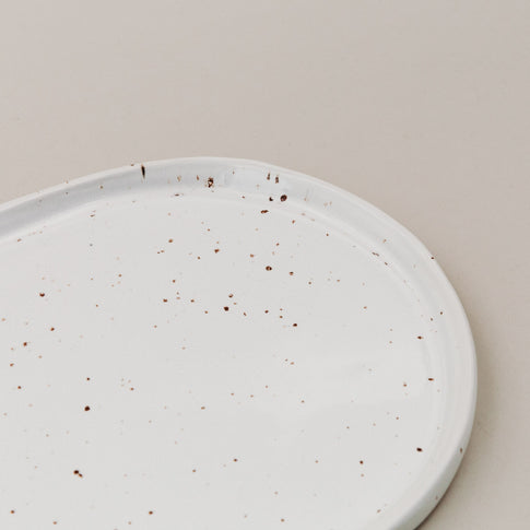 Detailansicht der Servierplatte Calma klein mit feinem braunem Sprenkelmuster im Randbereich
