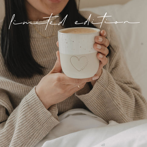 Frau hält Keramikbecher Mama mit Herzdetail, gemütlicher Moment zuhause, Limited Edition