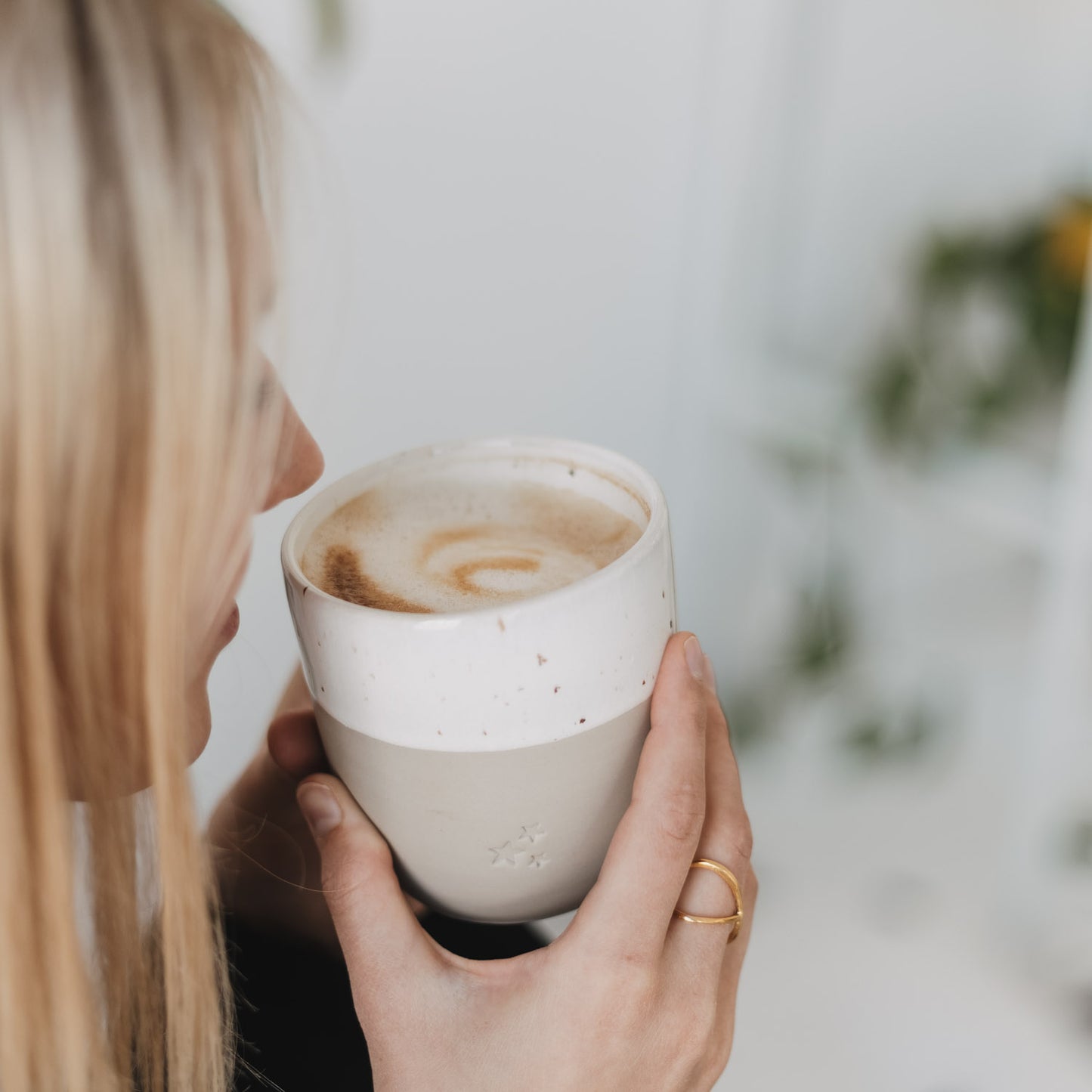 Person trinkt Kaffee aus Keramikbecher mit Sternen, stilvoller Alltagsbecher