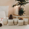Keramikbecher Set mit Weihnachtsprägung, dekoriert mit Orange, Tannenzapfen und Zuckerstange, festlich arrangiert