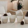 Set Keramikbecher mit Weihnachtsmotiven, dekoriert mit Tannenzapfen, stilvolle winterliche Tischdekoration