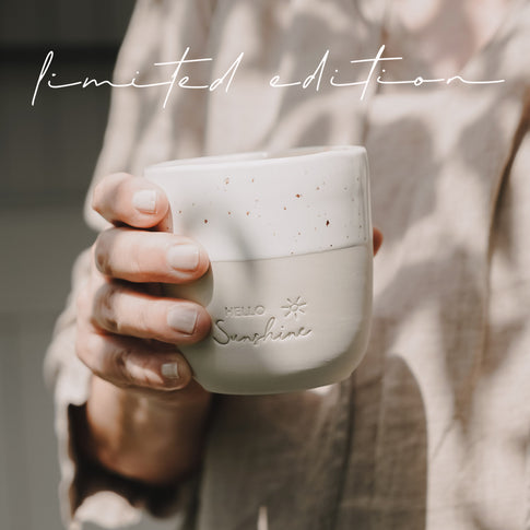 Hand hält Keramikbecher „Hello Sunshine“ Limited Edition, Mini Mug in Beige Weiß