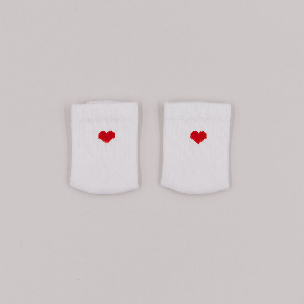 Weiße Babysocken mit gesticktem rotem Herz auf der Vorderseite, liebevoll nebeneinander auf hellgrauem Hintergrund platziert.