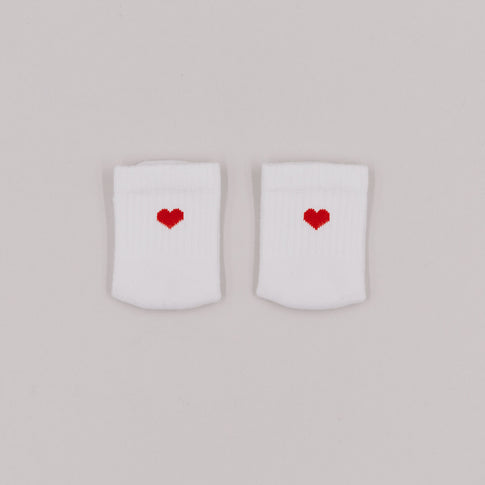 Weiße Babysocken mit gesticktem rotem Herz auf der Vorderseite, liebevoll nebeneinander auf hellgrauem Hintergrund platziert.
