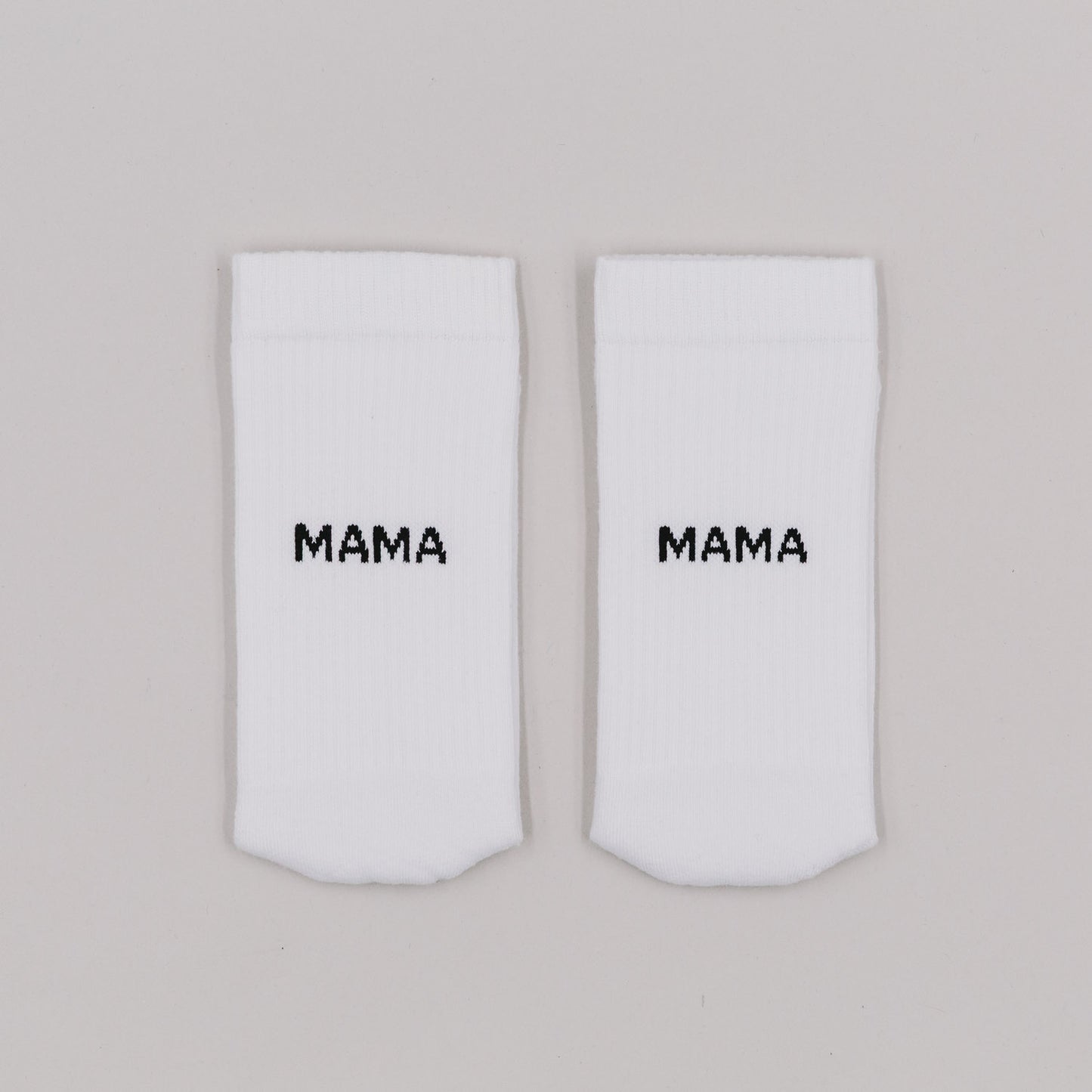 Zwei weiße Socken mit schwarzem Mama-Schriftzug – schlichtes und liebevolles Design für Mamas.