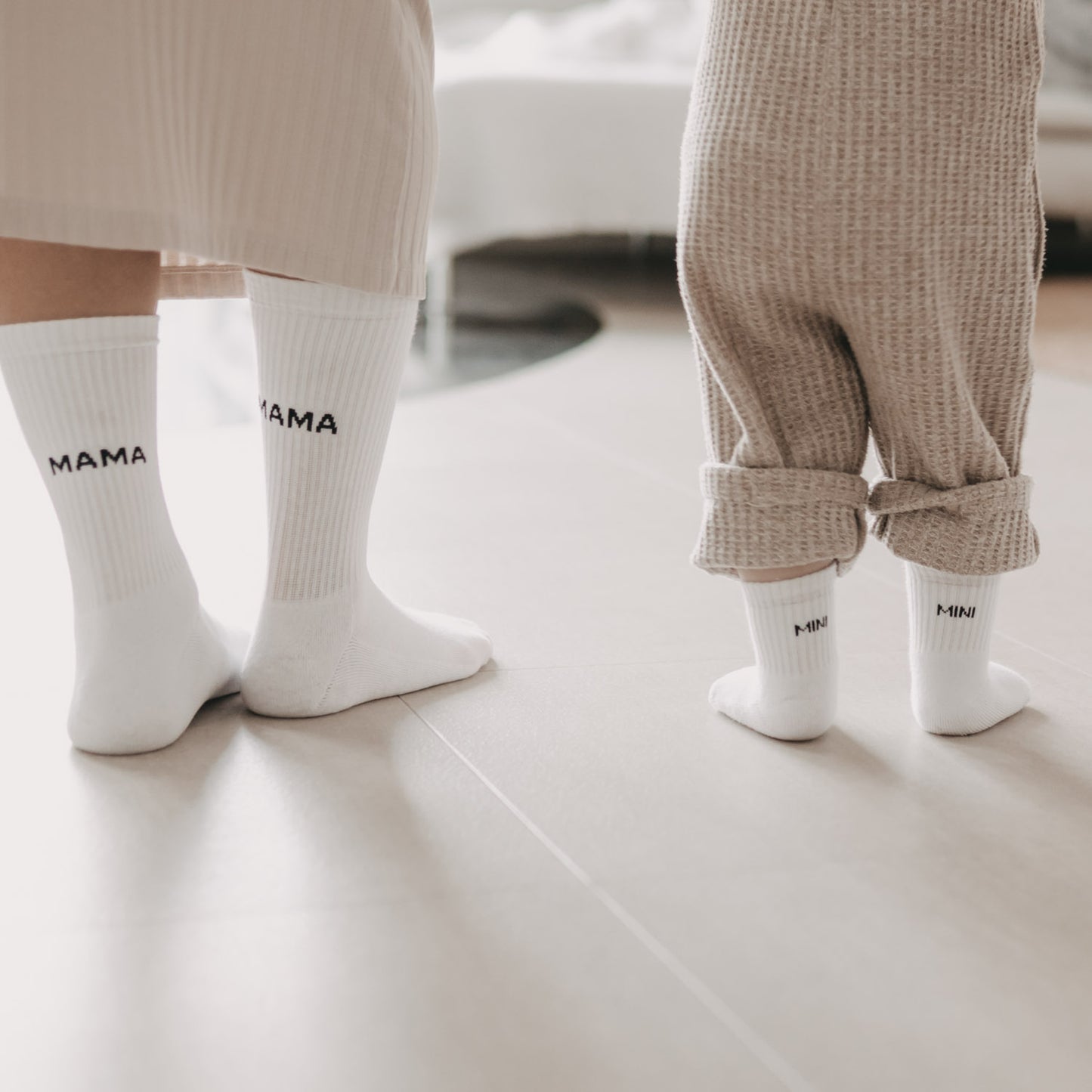 Mama und Kind stehen nebeneinander mit passenden weißen Socken – Mama und Mini im Partnerlook.