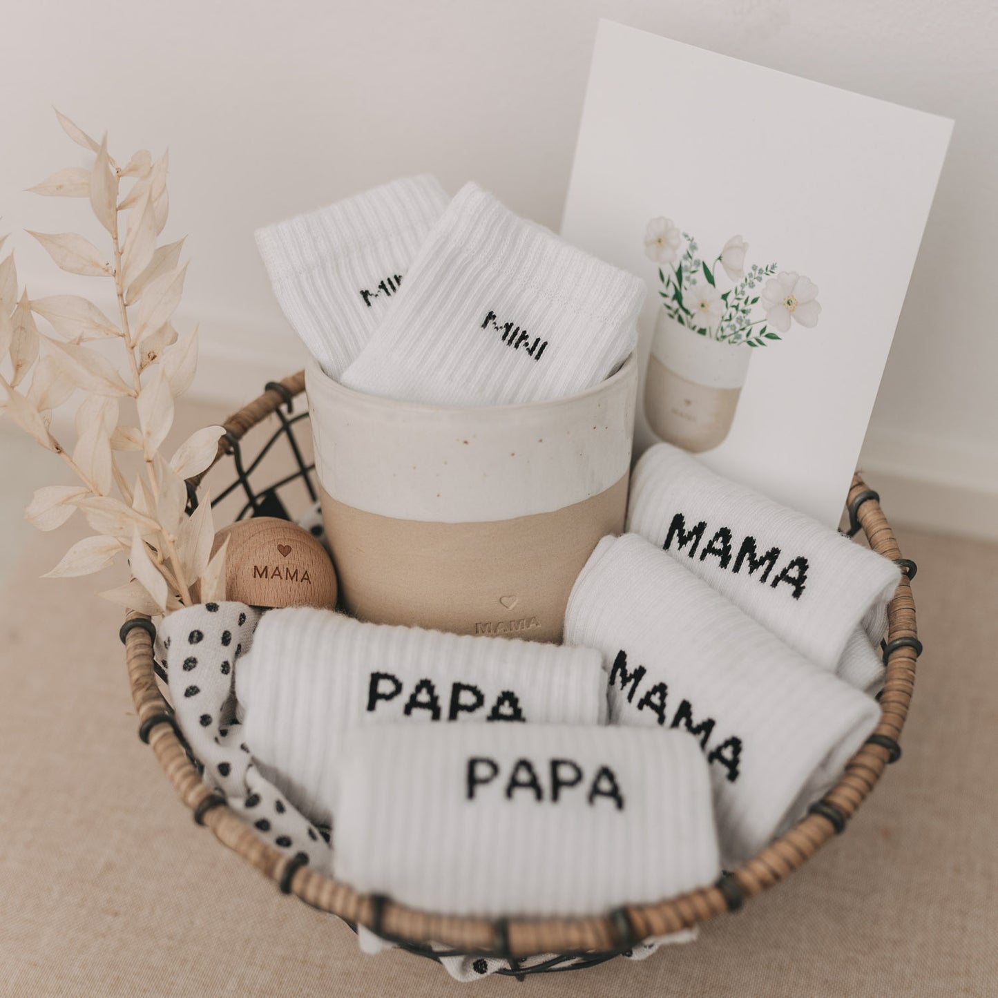 Geschenkkorb mit weißen Socken für Mama, Papa und Mini – liebevoll arrangiert mit Karte und Dekoration.