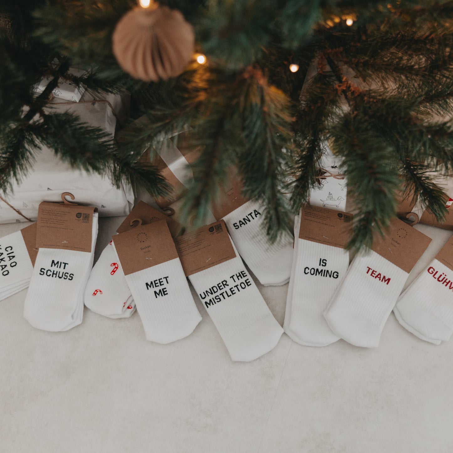 Auswahl verschiedener Eulenschnitt Weihnachtssocken unter dem Weihnachtsbaum, u.a. Ciao Kakao mit Schuss