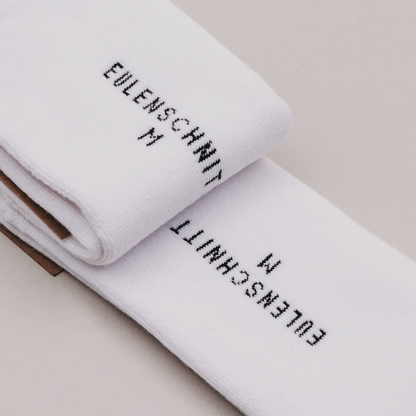 Detailansicht der eingestickten Größe „Eulenschnitt M“ auf der Fußsohle der Socken Ciao Kakao mit Schuss