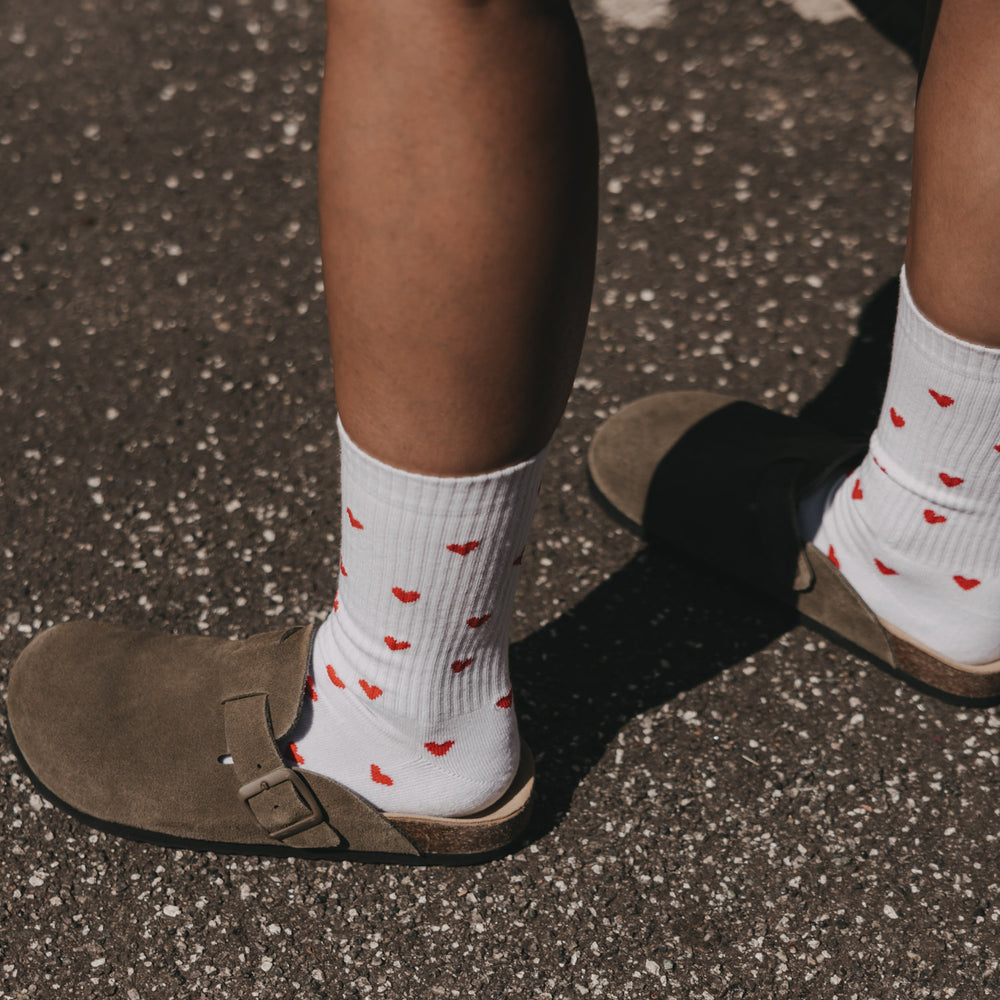 Weiße Eulenschnitt Socken mit roten Herzen, getragen zu braunen Sandalen.