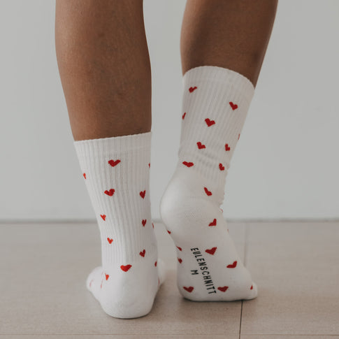 Weiße Eulenschnitt Socken mit roten Herzen und Logo auf der Sohle.