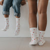 Erwachsene und Kind tragen weiße Eulenschnitt Socken mit roten Herzen.