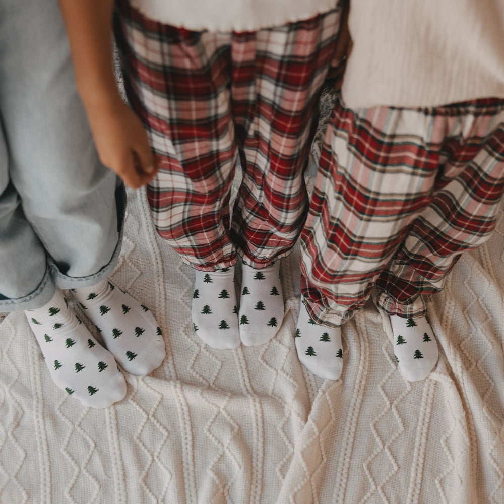 Erwachsene und Kinder tragen weiße Eulenschnitt Socken mit grünen Tannen im Familienlook.