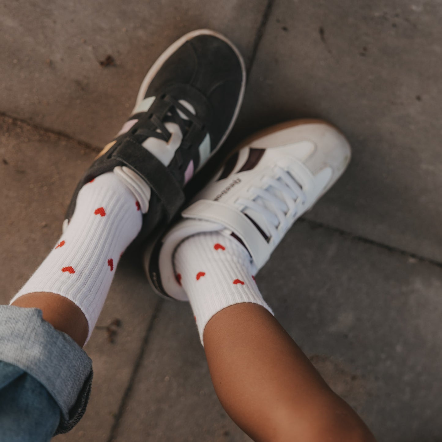 Weiße Eulenschnitt Kindersocken mit roten Herzen im Allover-Design und Sneakern.