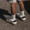 Weiße Eulenschnitt Kindersocken mit roten Herzen, getragen zu hellen Sneakern.